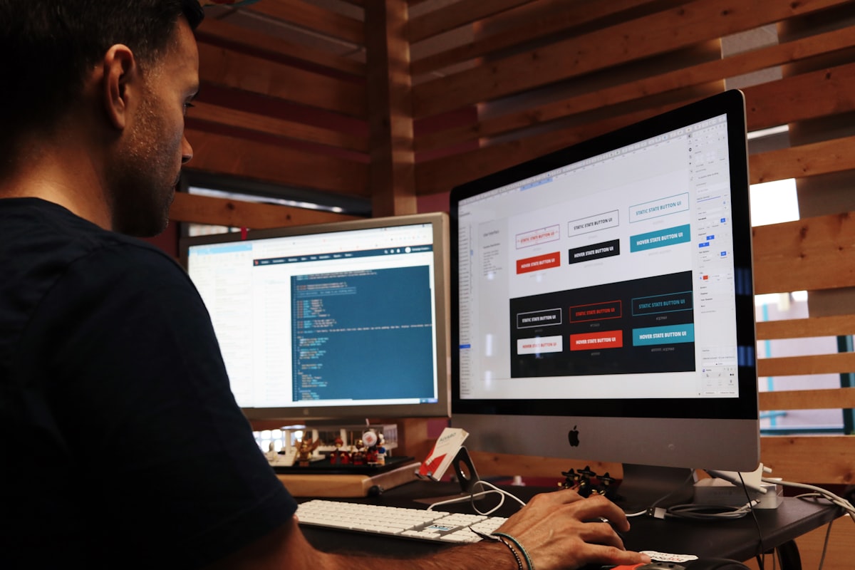Développeur analysant du code et une interface web sur deux écrans