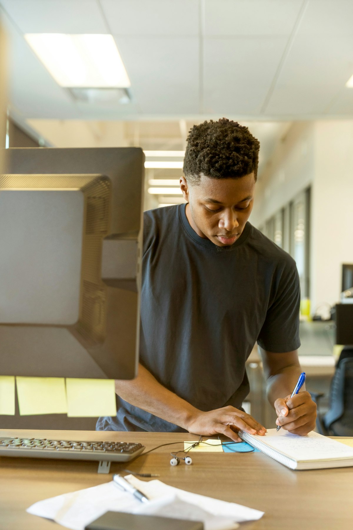 Entrepreneur notant ses idées dans un carnet à côté de son ordinateur